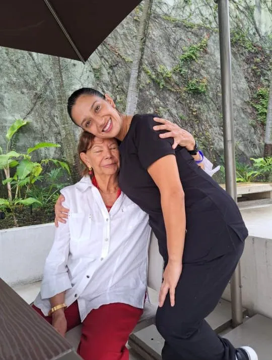 Cuidadora de NeuroCer abrazando a una adulta mayor sonriente