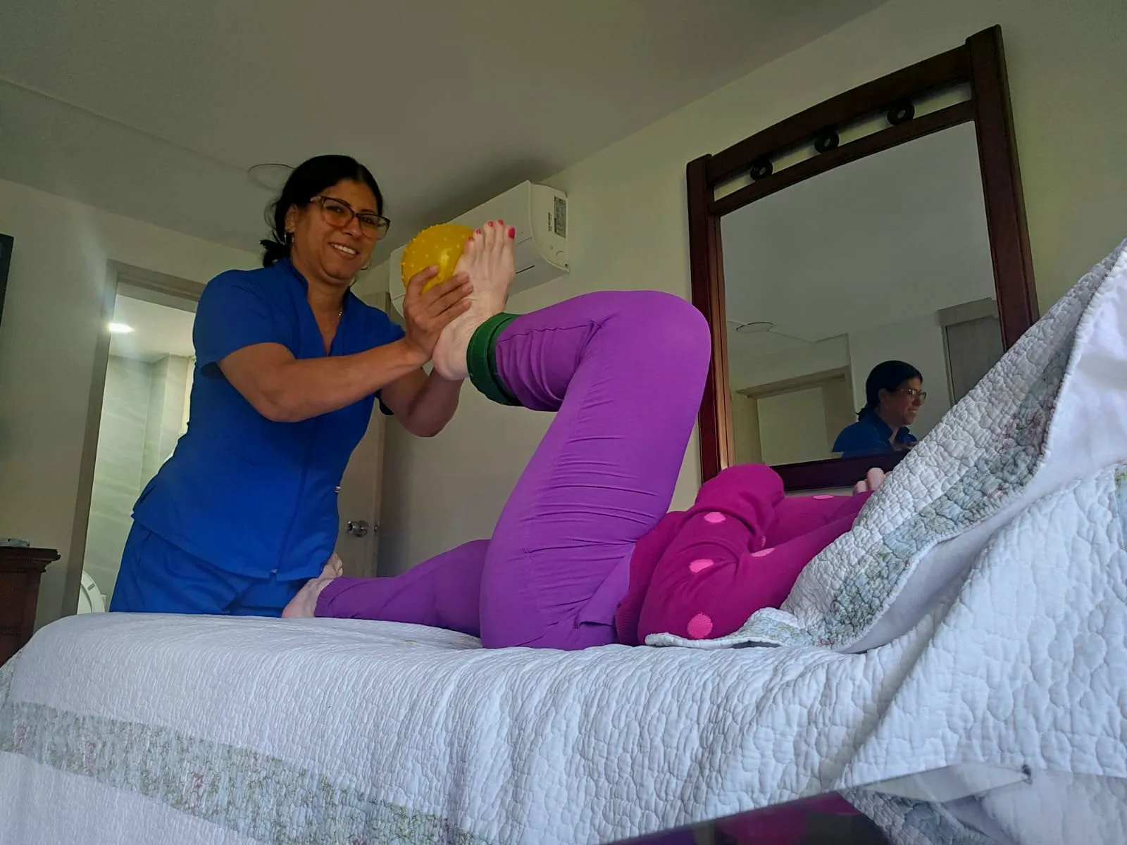 Fisioterapeuta ejercitando las piernas de una paciente en su cama